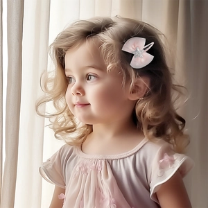 Detail of pink bow hair clip with silver glitter star worn by a young girl