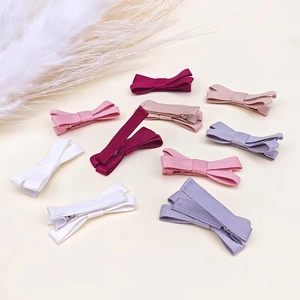 Flat lay of cotton linen bow hair clips in various soft pastel colors on beige background