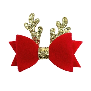 Détail d'une pince à cheveux de Noël avec nœud en feutre rouge et bois de renne dorés pailletés