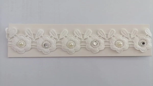 Detail of white lace headband featuring embroidered flowers with pearls and rhinestones