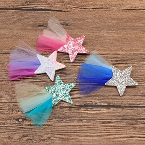 Détail de quatre barrettes étoiles à paillettes avec queues en dentelle sur bois