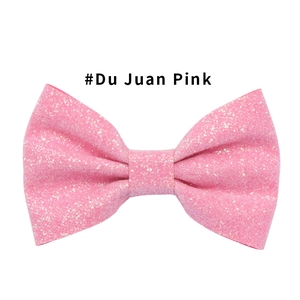 Dettaglio di un fermaglio per capelli a fiocco rosa glitterato con trama scintillante