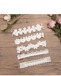 Detail of five white lace headbands with rhinestones and pearls on a wood background