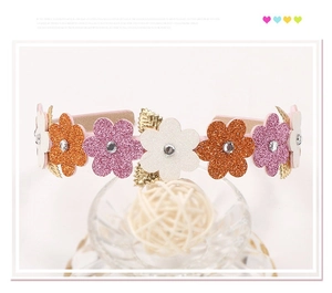 Close-up of glittered flower headband with rhinestones and golden leaf accents