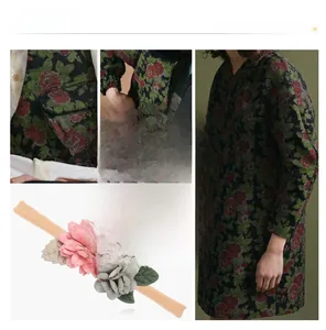 Détail de fleurs en tissu rose et gris sur un bandeau souple en nylon pour bébé