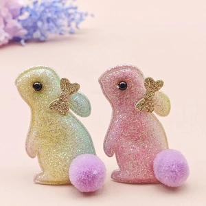 Détail de barrettes lapin à paillettes avec pompons mauves et nœuds dorés