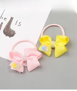 Détail de bandeaux à nœuds roses et jaunes avec perles fantaisie et strass brillants