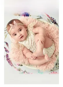 Baby trägt ein rosa Kunstleder-Schleifenstirnband auf weichem Plüschhintergrund