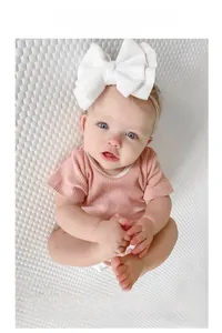 Detail of baby headband featuring large white textured knit bow and soft elastic nylon band