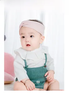 Close-up of pink knitted wide headband showing cross-knot texture on infant model