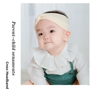 Close-up of baby wearing a cream soft ribbed knit cross headband with a twisted knot design