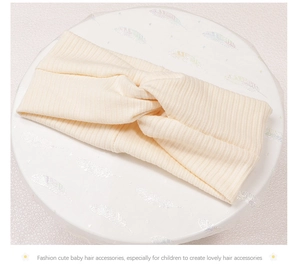 Detail view of a cream white knitted twist knot headband for baby and children