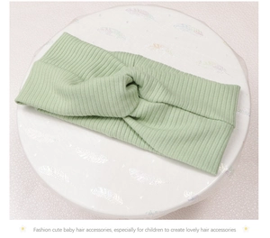Detail shot of light green knitted ribbed baby headband featuring a stylish twist knot design