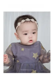 Détail d'un bébé portant un bandeau en dentelle rose avec des fleurs en perles