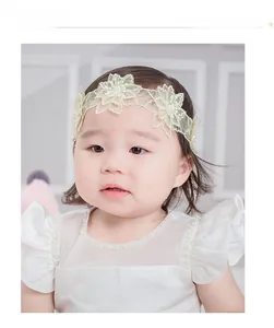 Détail d'un bandeau en dentelle pour bébé avec pétales en tulle et perles élégantes