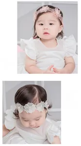 Détail d'un bandeau en dentelle pour bébé avec fleurs brodées et perles pour nouveau-nés