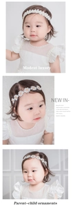 Détail d'un bandeau pour bébé en dentelle avec fleurs de marguerites blanches et perles