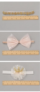 Détails de trois bandeaux bébé avec nœuds en tulle et couronnes dorées sur échelle