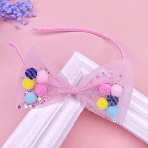 Dettaglio di cerchietto rosa con fiocco in rete, pompon colorati e paillettes per bambine