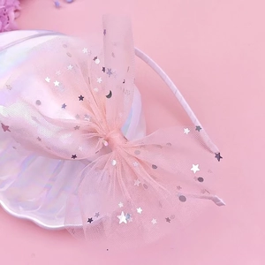 Dettaglio del cerchietto con fiocco in tulle rosa e paillettes argento di stelle e lune
