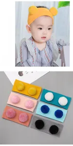 Detail von Baby-Strickstirnbändern mit Doppelpompons in verschiedenen bunten Farben