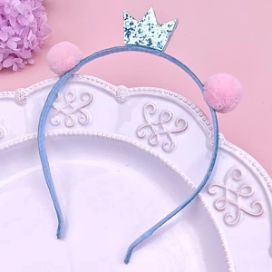 Détail d'un serre-tête enfant avec couronne de paillettes bleues et pompons roses