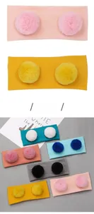 Detailansicht von gestrickten Baby-Stirnbändern mit Pompons in vielen bunten Farben