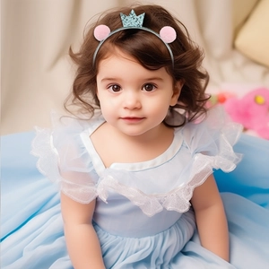 Détail d'un serre-tête avec couronne pailletée bleue et pompons roses pour fillette
