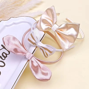Drei elegante Kinder-Haarreifen mit Satin-Schleifen und gestreiften Mustern auf einem Tablett