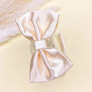 Nahaufnahme eines Satin-Haarreifs mit großer Schleife in Champagnergold auf Glas