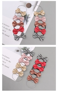 Detailansicht der schimmernden Schleifen-Haargummis in Gold, Rosa und Metallic-Rot