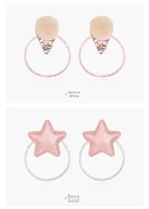 Detail of pom-pom and star sequin hair ties in almond white and rose gold tones
