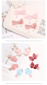 Detalle de pinzas para el pelo con lazo rosa, perlas colgantes y colgantes de corazón