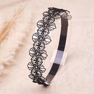 Detail of black lace headband featuring intricate embroidered cutout daisy flower patterns