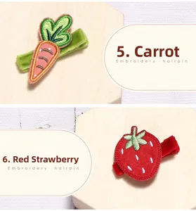 Détail de barrettes brodées main aux motifs carotte et fraise sur pinces en velours
