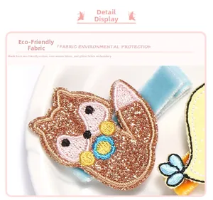 Détail de barrettes brodées renard et oiseau en tissu pailleté respectueux de l'environnement