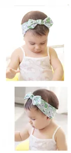 Close-up of baby girl wearing floral bow headband in soft cotton fabric with green leaf pattern