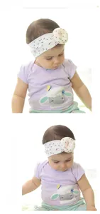 Floral baby headband detail showing pink flower ornament on a soft white elastic band