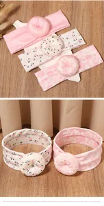 Detailed view of three elastic pink floral baby headbands with donut-shaped bow accents