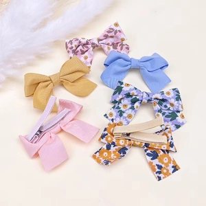 Lot de 6 barrettes nœuds en tissu à fleurs et couleurs unies pour enfants sur fond blanc