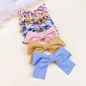 Détail d'un lot de 6 barrettes à nœuds fleuris et unis en tissu pour petites filles