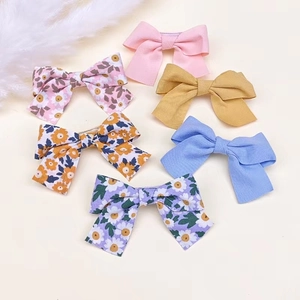 Détails d'un lot de barrettes à nœuds pour enfants avec motifs floraux et couleurs unies
