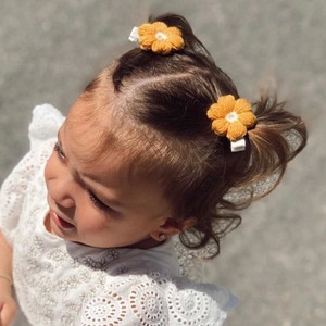 Detalle de horquillas de flores amarillas tejidas a mano en el pelo de una niña