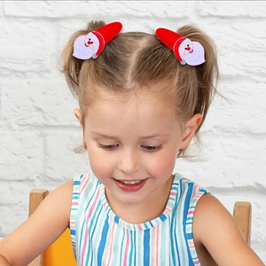 Close-up of a young girl wearing festive red Santa Claus felt hair clips on her ponytail