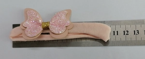Detail eines rosa Baby-Stirnbandes mit Pailletten-Schleife und Ledertextur