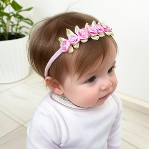 Detail eines rosa Satin-Baby-Haarbandes mit Seidenrosen und weißen Perlenakzenten