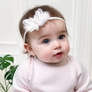 Detail eines weißen Baby-Spitzenstirnbands mit Perlen und Kunstfell-Applikation