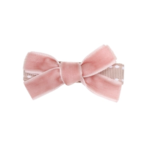 Detail of a pink velvet bow hair clip with heart pendant and polka dot ribbon texture