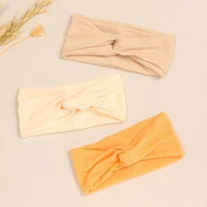 Close-up of soft modal knot baby headbands in apricot, cream white, and orange set