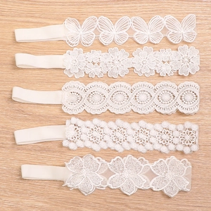 5-pack baby white lace headbands with floral and butterfly embroidery on wood background